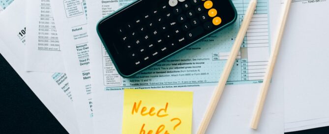 calculator and tax forms with a need help post it note